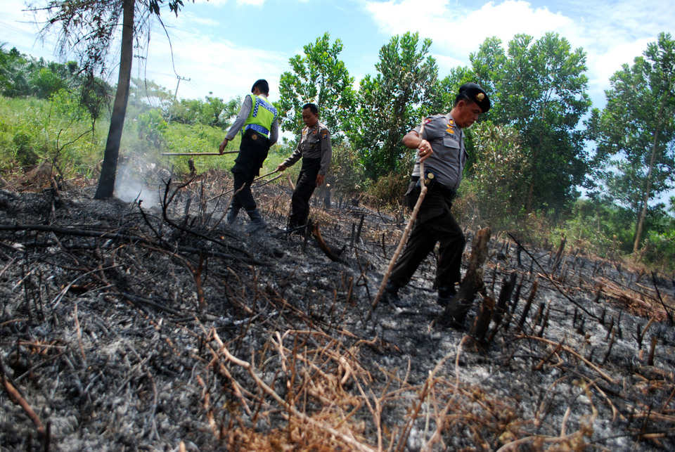 Police officers inspect land which had been intentionally burned while patrolling forest fires in Pekanbaru, Riau, on Tuesday (19/07). Police officers routinely patrol the vicinity in order to prevent and control the spread of forest and land fires that often occur in Riau. (Antara Photo/Rony Muharrman)