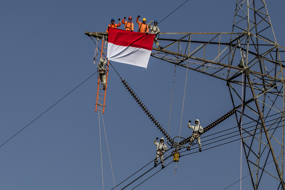 Workers from state power company PLN fly the Indonesian national flag at a high-voltage transmission tower in Bogor, West Java, on Tuesday (26/07). (Antara Photo/Muhammad Adimaja)