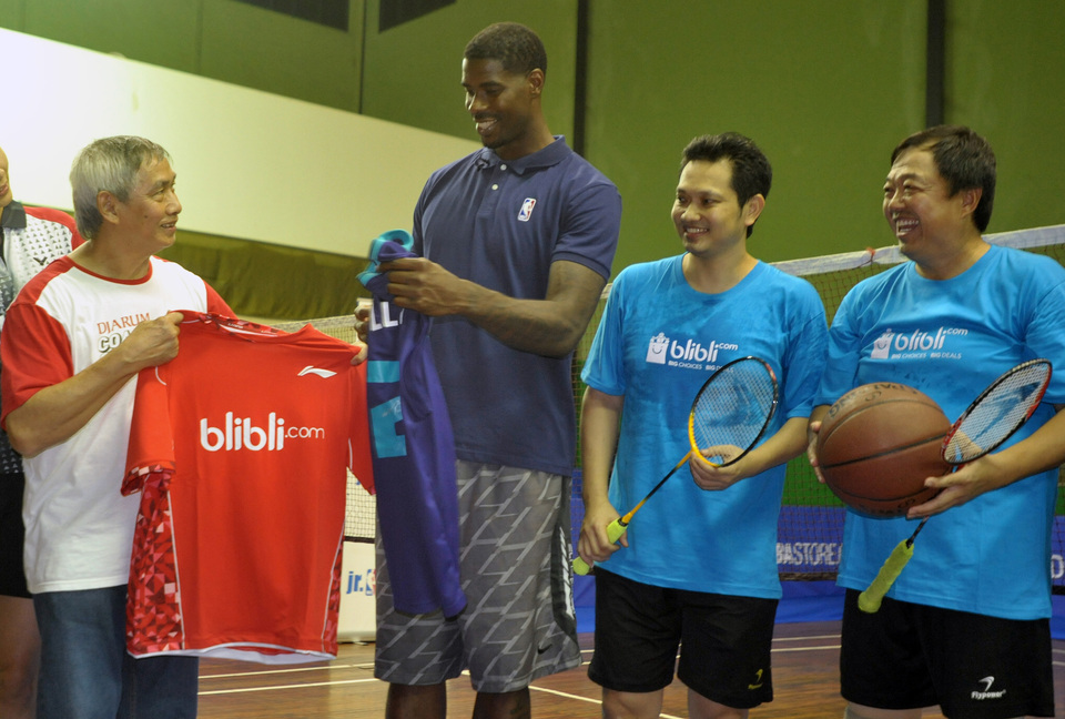 American professional basketball player Marvin Williams, center, exchanges jerseys with badminton legend Christian Hadinata, as former top shuttlers Hariyanto Arbi and Eddy Hartono look on. (Antara Photo/Audy Alwi)