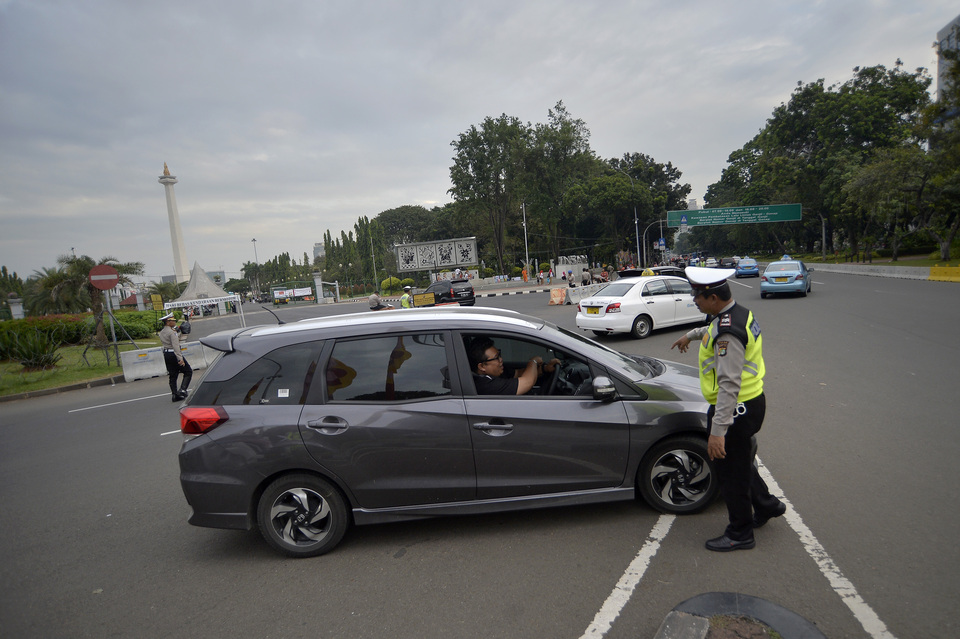 FILE - A traffic policeman stops a car for violating the license plate-based driving restriction in Jakarta. (Antara photo)