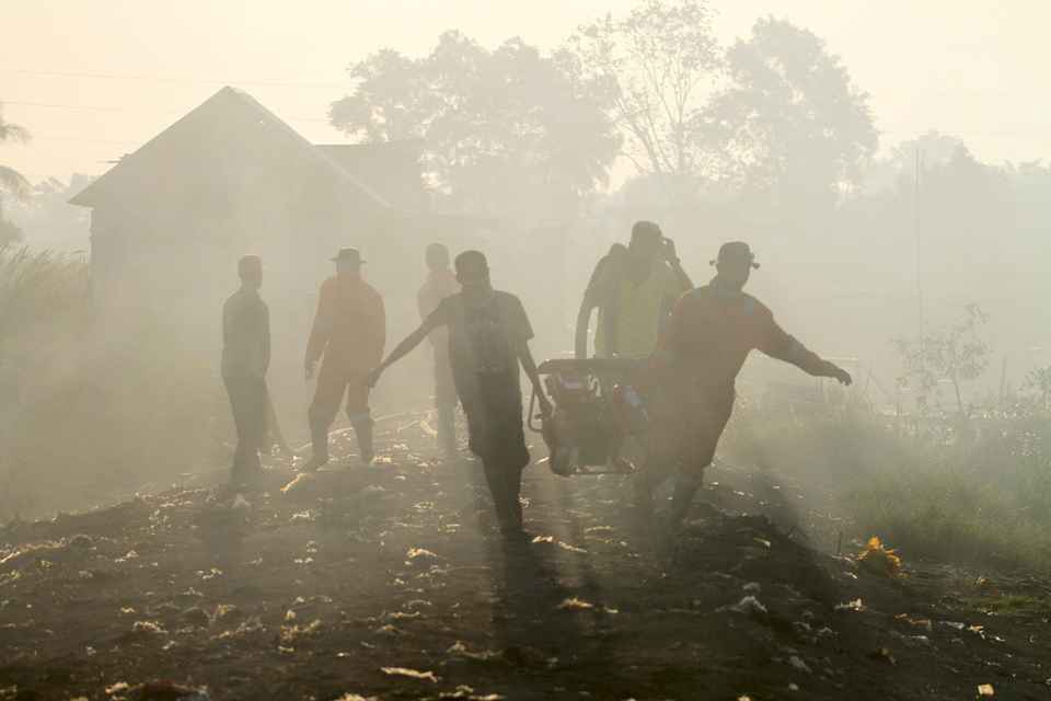 Officers of the Regional Disaster Management Agency (BPBD) in Ogan Ilir, South Sumatra, carry a suction machine while extinguishing fires on Wednesday (17/08). The South Sumatra Governor has set a state of emergency in anticipation of fires until November. (Antara Photo/Nova Wahyudi)