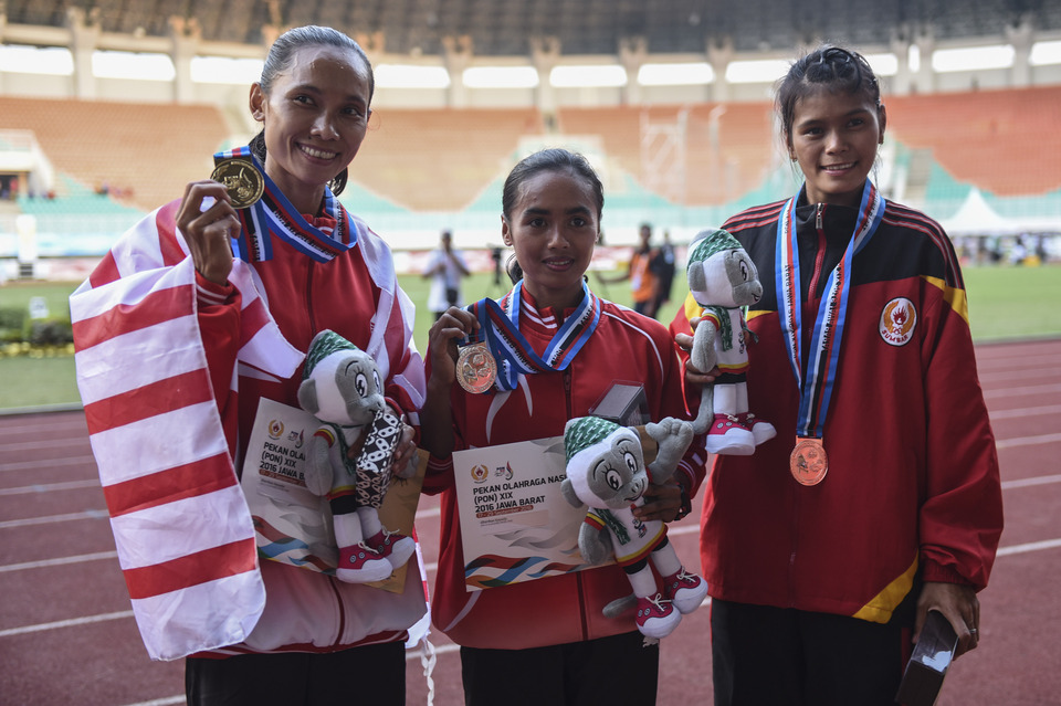 Jakarta athlete Rini Budiarti, left, poses with the gold medal she won in the women's 5,000 m at the 19th National Sports Week on Thursday (22/09). (Antara Photo/Hafidz Mubarak A.)