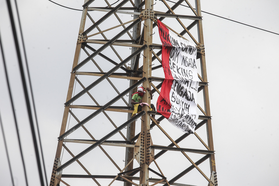 A Jakarta resident climbs an electricity tower in Senen, Central Jakarta, to protest against the killing of street kids — reportedly by criminals backed by a military officer. (Antara Photo/Muhammad Adimaja)