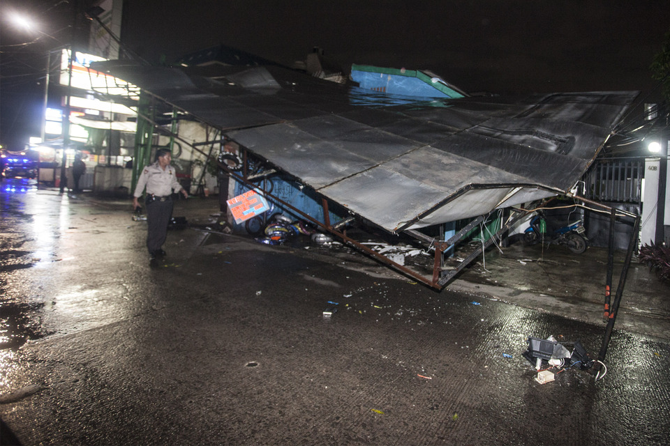 A police officer inspects a billboard which collapsed in Kemang, South Jakarta, on Sunday (25/09) after heavy rains and strong winds hit the area. (Antara Photo/Muhammad Adimaja)

