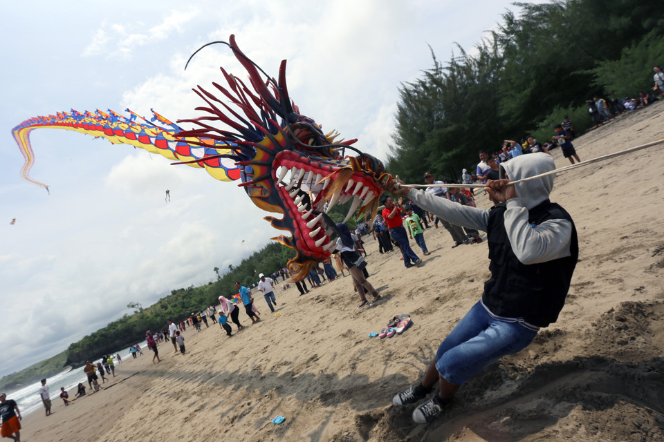 A participants holds a large kite during a festival in Serang beach, Blitar, East Java, on Sunday (25/09). The festival was attended by around 115 participants from kite clubs around the country with the aim to boost tourism to the area. (Antara Photo/Irfan Anshori)

