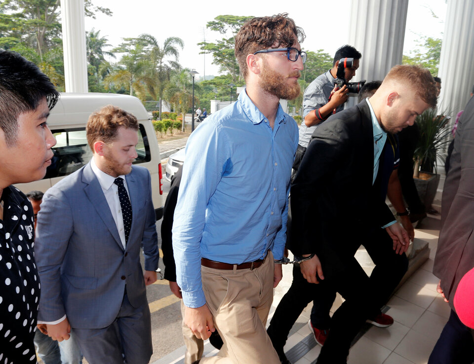 Australian men, part of a group of nine who were detained for stripping down to their underwear at last Sunday's Formula One Malaysian Grand Prix, are escorted as they arrive at the Magistrate Court in Sepang, Malaysia October 6, 2016. (Reuters Photo/Lai Seng Sin)