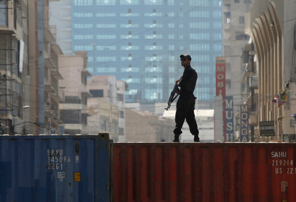 A policeman stands guard on a shipping container used to block roads in Karachi, Pakistan. (Reuters Photo/Akhtar Soomro)