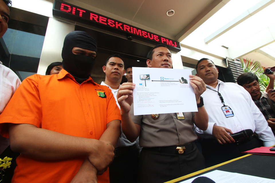 Jakarta Police spokesman Sr. Cmr. Awi Setiyono, center, stands next to a masked suspect who purportedly 
displayed pornographic material on a so-called videotron, or outdoor video advertising screen in South Jakarta, on Friday (30/09). (Antara Photo/Rivan Awal Lingga)