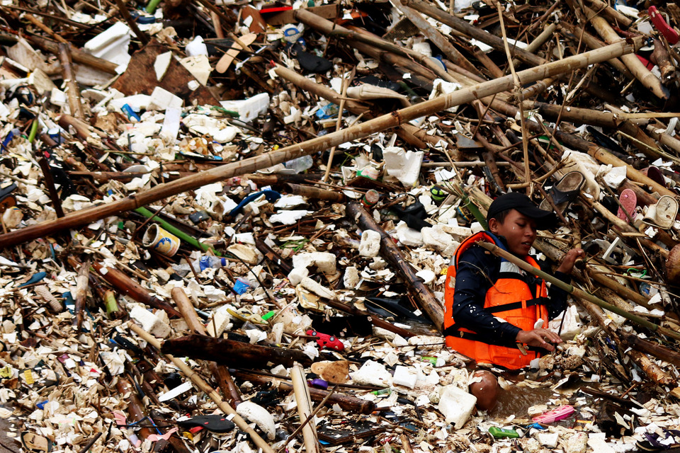 A sanitation worker removes garbage clogging the Manggarai watergate in the Ciliwung River in Jakarta on Tuesday (11/10), to prevent it from overflowing as a result of heavy rains. (Antara Photo/Rivan Awal Lingga)