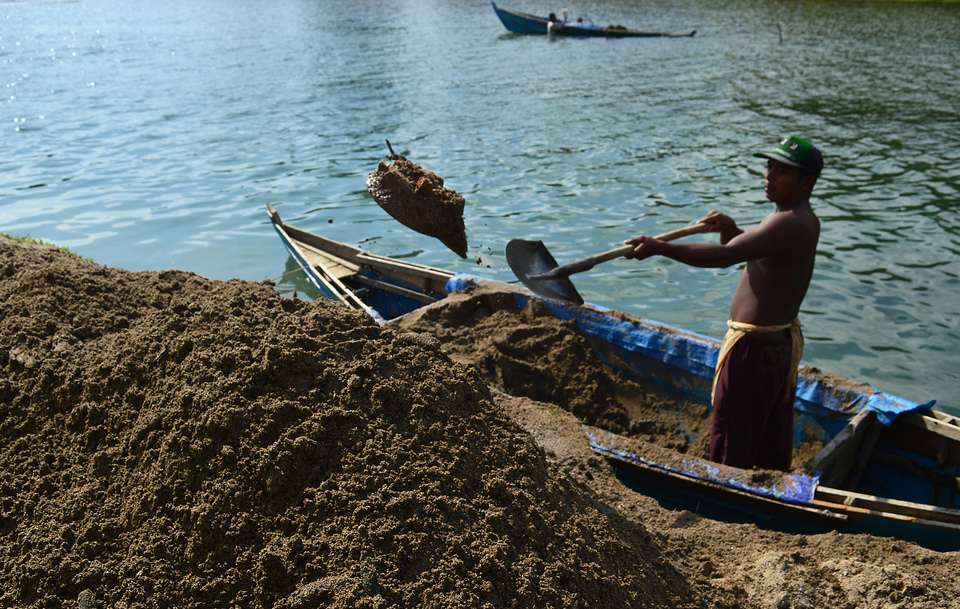 A worker offloads sand from a boat near Blangpidie in Southwest Aceh district, Aceh, on Sunday (02/10). The removal of river sand, which is used as building material and sells for Rp 250,000 ($19) per truck load, is considered to lead to environmental degradation. (Antara Photo/Suprian)