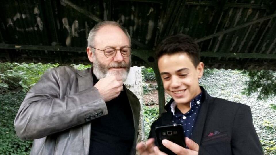 Games of Thrones star Liam Cunningham smiles together with his supporter Syrian migrant Hussam Alheraky as he made a surprise vist in Stuttgart, Germany, October 11, 2016. (Reuters Photo/Reuters Tv)
