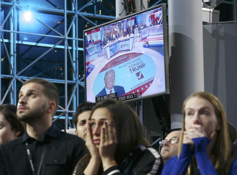 Supporters of Democratic presidential nominee Hillary Clinton watch and wait, with a Donald Trump image on a screen at rear, at her election night rally in New York, United States, on Tuesday (08/11). (Reuters photo/Carlos Barria)