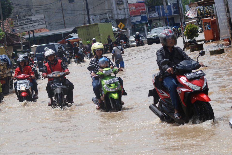 Motorcyclists try to pass a street inundated by flood water in Dayeuhkolot, Bandung, West Java, on Monday (14/11). The flood was caused by heavy rainfalls and overflowing water from the Citarum River. (Antara Photo/Fahrul Jayadiputra)