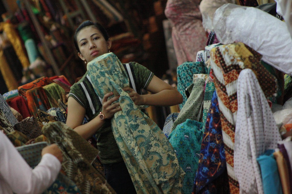 This file photo from 2018 shows a woman picks up a bundle of fabrics at a store in Pasar Baru market in Jakarta. (JG Photo/Yudhi Sukma Wijaya)