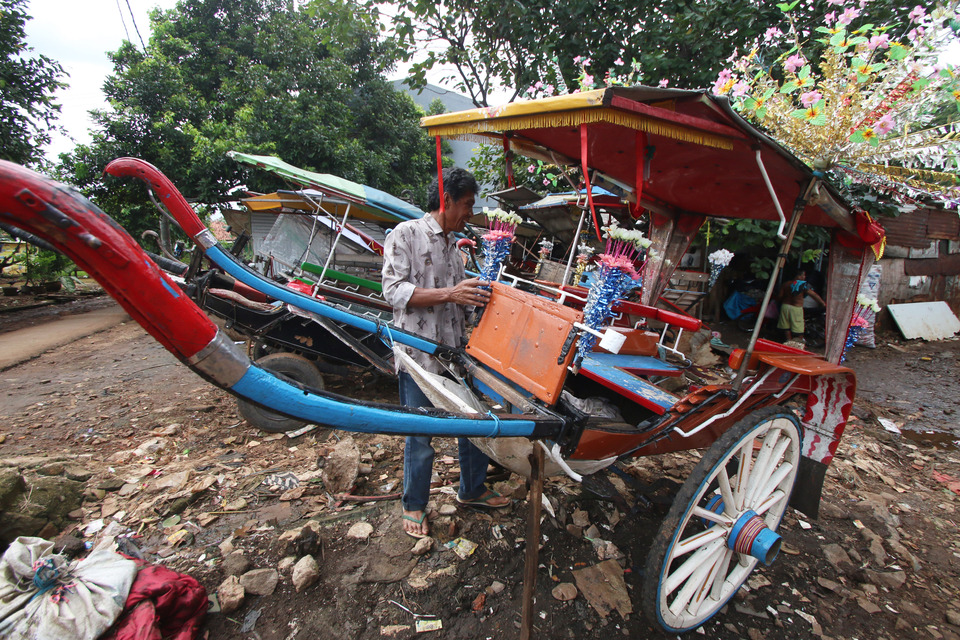 A drivers cleans his delman wagon in Jakarta on Tuesday (06/12). Competition in public transport, particularly with the advent of app-based transport, has seen traditional transport like wagons marginalized. (Antara Photo/Rivan Awal Lingga)

