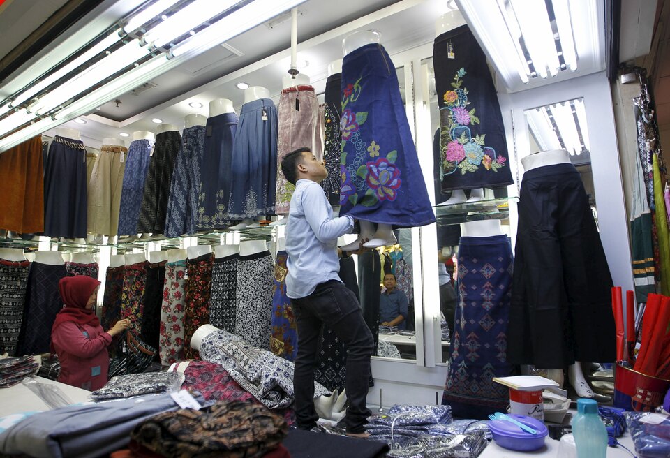 A vendor hangs a skirt at a clothing stall in a market in Jakarta. (Reuters Photo/Garry Lotulung)