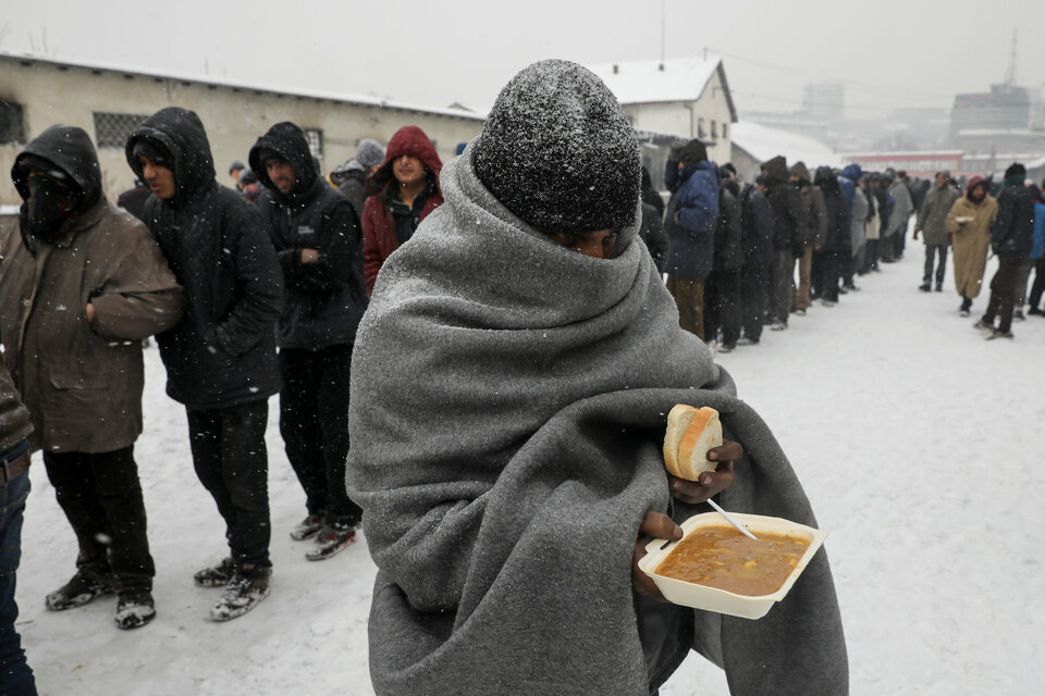 A migrant carries a plate of free food during a snowfall outside a derelict customs warehouse in Belgrade, Serbia, on Jan. 11. (Reuters Photo/Marko Djurica)
