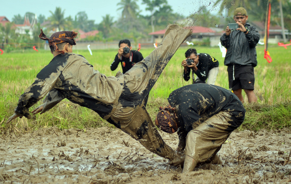 Martial arts athletes demonstrate the 'basilek' fighting technique in the rice fields of Solok, West Sumatra, on Sunday (22/01). This form of martial arts is being promoted in an effort to preserve the local tradition of silek tuo, which has been proven to be less than popular among the youth. (Antara Photo/Iggoy el Fitra)
