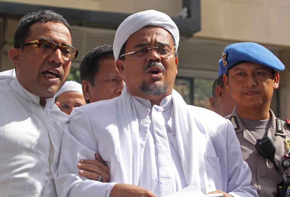 Islamic Defenders Front (FPI) leader Rizieq Shihab, center, speak to reporters after undergoing questioning at the Jakarta Police headquarters in January. (Antara Photo/Reno Esnir)