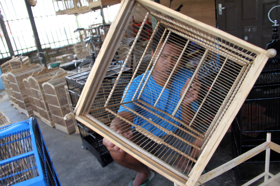 Perajin merakit sangkar burung berbahan kayu jati di Tulungagung, Jawa Timur, Kamis (4/1). Perajin mengaku persaingan tidak sehat antar pedagang dan membanjirnya produk pabrikan menyebabkan sangkar burung tradisional yang dipatok harga mulai Rp15 ribu hingga Rp120 ribu per unit tersebut kesulitan pemasaran. ANTARA FOTO/Destyan Sujarwoko/pras/16