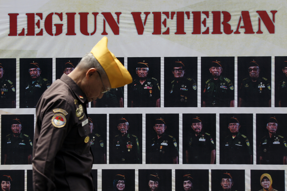 A veteran walks by the portraits of his comrades in arms in Bandung, West Java, during the Veterans Day ceremony on Tuesday (10/01). (Antara Photo/Agus Bebeng)