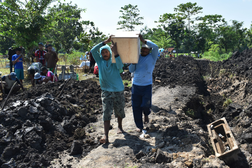 Men relocate a cemetery in Purworejo village in Madiun, East Java, on Wednesday (11/01) to accommodate Trans-Java Toll Road construction. (Antara Photo/Siswowidodo)

