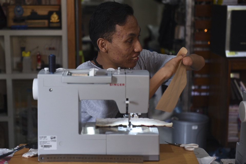 A disabled craftsman makes a bag on a sewing machine in Surabaya, East Java, on Wednesday (11/01). (Antara Photo/Zabur Karuru)