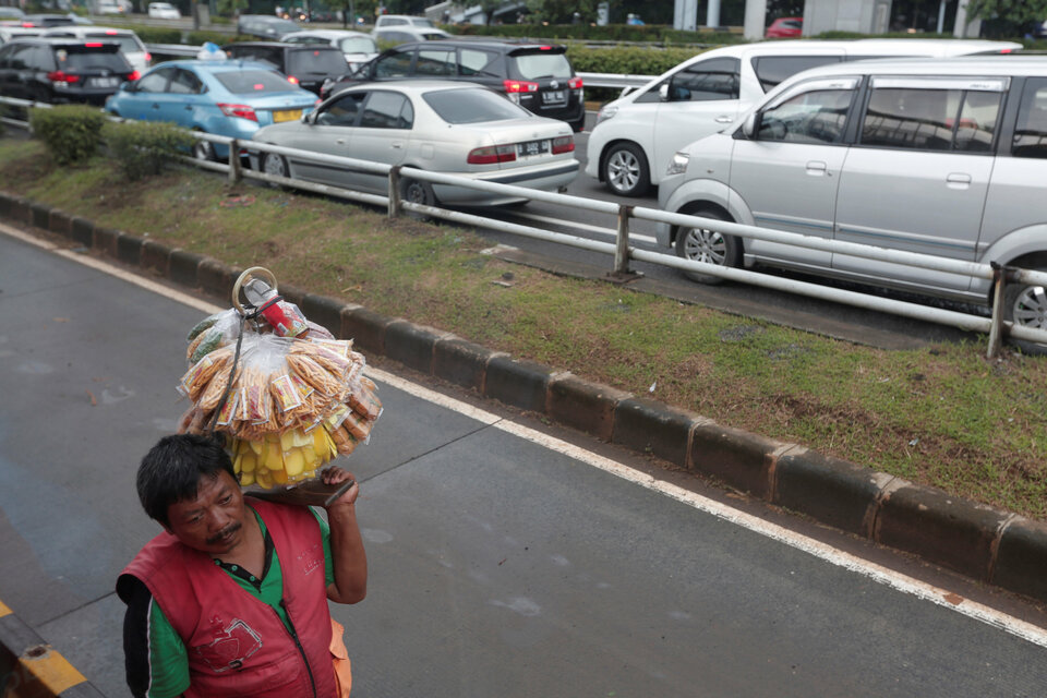 A street vendor carries food next to a traffic jam along a road in Jakarta, Indonesia February 1, 2017. Picture taken Feb. 1, 2017. (Reuters Photo/Beawiharta)