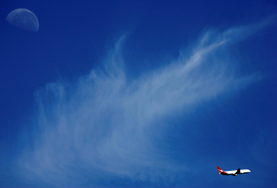 A Qantas passenger plane flies past the moon above Sydney. (Reuters Photo/David Gray)