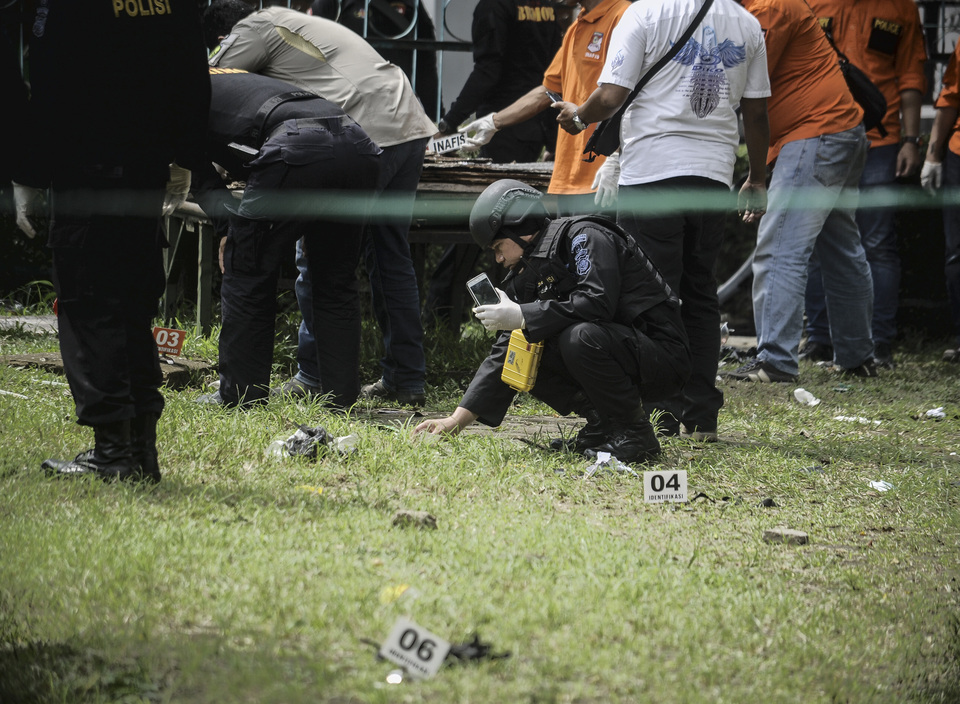 Members of the police bomb squad inspect the scene where a homemade bomb was detonated near Pandawa Park in Bandung, West Java, on Feb. 27. (Antara Photo/Novrian Arbi)