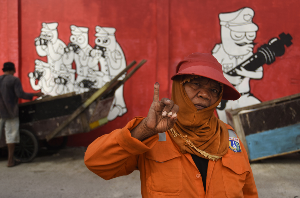 A street cleaner shows a finger dipped in ink, a sign that she had already cast her vote in the Jakarta gubernatorial election on Wednesday (15/02). (Antara Photo/Fanny Octavianus)