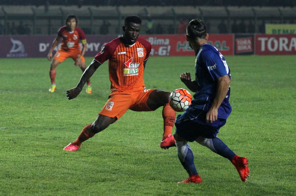 Pusamania's Dirkir Glay, left, anticipates an attempted cross by Persib Bandung's Kim Kurniawan during their President's Cup semifinal match in Bandung, West Java, on Sunday (05/03). (Photo courtesy of the PSSI)