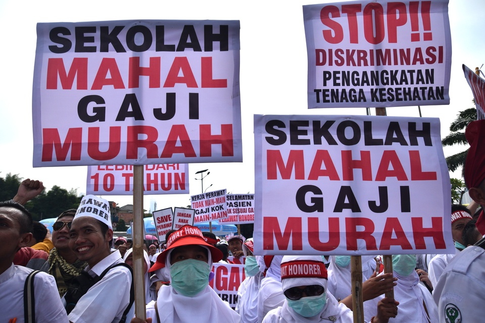 Members of the Indonesian National Nurses Association (PPNI) carry placards during a rally in front of the House of Representatives building in Jakarta on Thursday (17/03). (Antara Photo/Atika Fauziyyah)