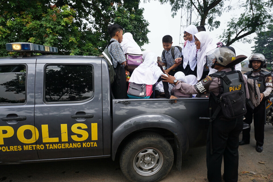 Members of the police transport students in Sangiang, Tangerang, Banten, on Thursday (09/03). There was a shortage of public transportation following clashes between of public transportation drivers and the drivers of ride-hailing services on Wednesday. (Antara Photo/Lucky R.)