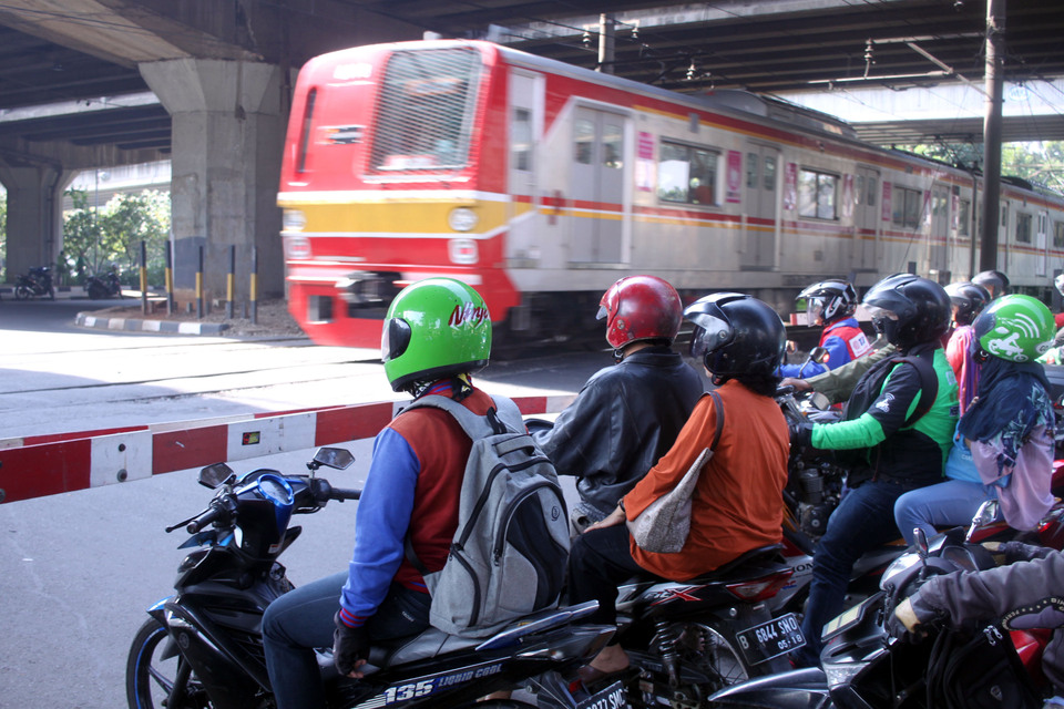 Motorists wait for a passing train at the Jalan Simatupang railroad crossing in South Jakarta on Thursday (09/03). The city government plans to close several crossing points, including those at Pejompongan, Pasar Minggu, Simatupang and Pondok Kopi, in an effort to improve the safety and efficiency of the city's rail system. (Antara Photo/Julius Satria Wijaya)