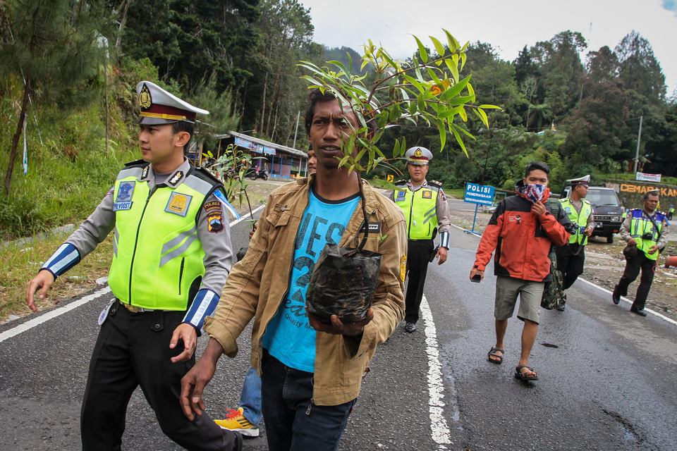 Police 'penalize' motorists who violate traffic ordinances by accompanying them to plant trees during the 2017 Operasi Simpatik Candi in Cemoro Kandang, Central Java, on Monday (13/03). (Antara Photo/Mohammad Ayudha)
