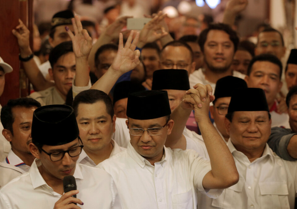 Former Indonesian education minister Anies Baswedan (C) holds the hand of Gerindra party chief Prabowo Subianto (R) as Baswedan running mate Sandiaga Uno (L) talks to reporters after voting in the Jakarta governor election in Jakarta, Indonesia April 19, 2017. (Reuters Photo/Beawiharta)