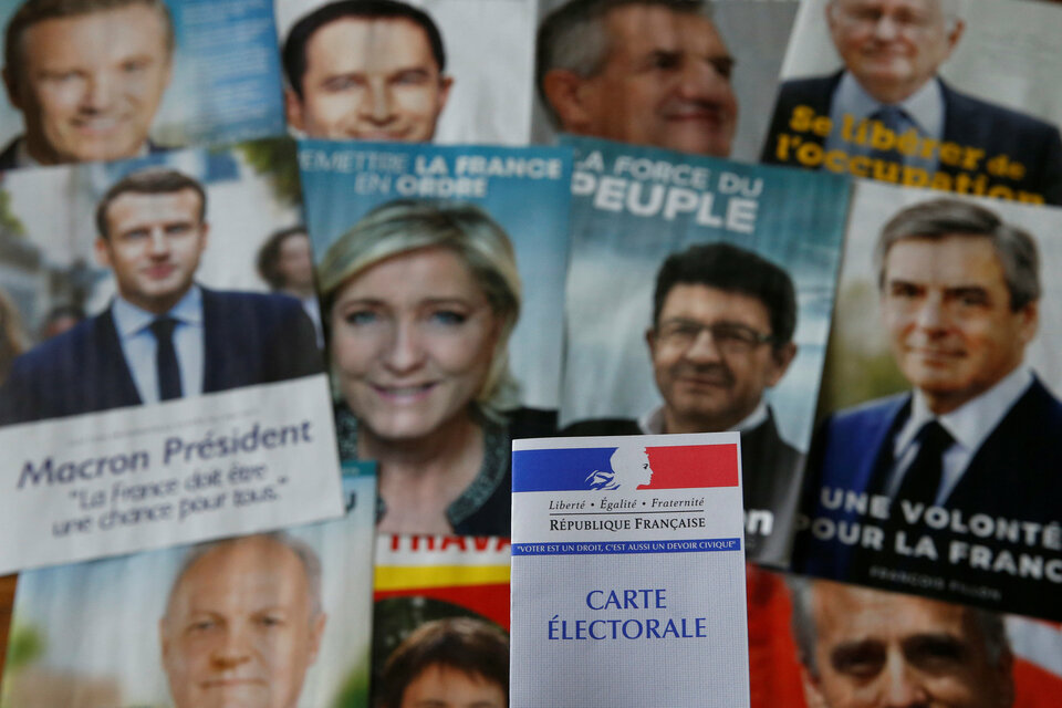A photo illustration shows a French voter card in front of pictures of the candidates for the French presidential election, April 22, 2017. (Reuters Photo/Pascal Rossignol)