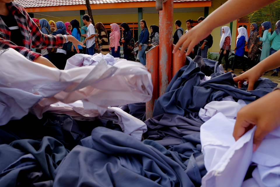 Some students shake hands with teachers while others hand in their uniforms following the national exam at a school in Makassar, South Sulawesi, on Thursday (06/04). The students decided to donate their school uniforms that are still in good condition to new students who will enroll at the school. (Antara Photo/Sahrul Manda Tikupadang)