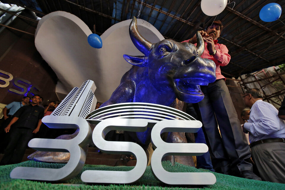 A man ties a balloon to the horns of a bull statue at the entrance of the Bombay Stock Exchange, or BSE, while celebrating the Sensex index rising to over 30,000, in Mumbai, India, on April 26. (Reuters Photo/Shailesh Andrade)