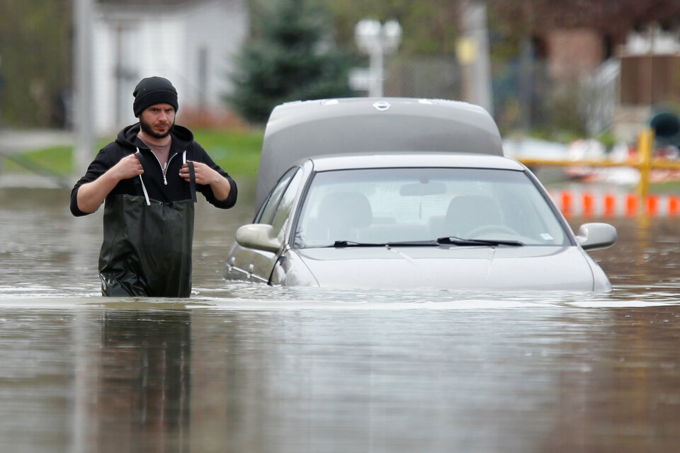 A man walks past an abandoned car on a flooded residential street in Gatineau, Quebec, Canada, on May 4. (Reuters Photo/Chris Wattie)