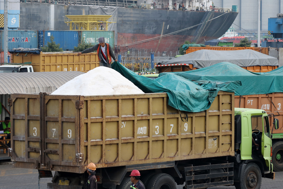 A worker covers imported salt from Australia with tarpaulin at Tanung Perak Port in Surabaya. (Antara Photo/Didik Suhartono)