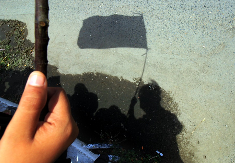 The reflection of a university student protesting against exorbitant tuition fees is seen on a street in Lhokseumawe, Aceh, during a demonstration on National Education Day on Tuesday (02/05). (Antara Photo/Rahmad)