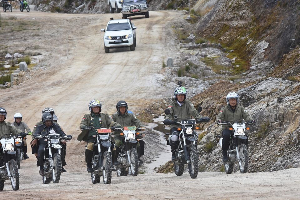 FILE - President Joko Widodo, second right, inspect the construction of Trans Papua Road using a dirt motorcycle along the Wamena-Habema section in Jayawijaya Regency on May 10, 2017.  (Photo courtesy of Public Works Ministry)