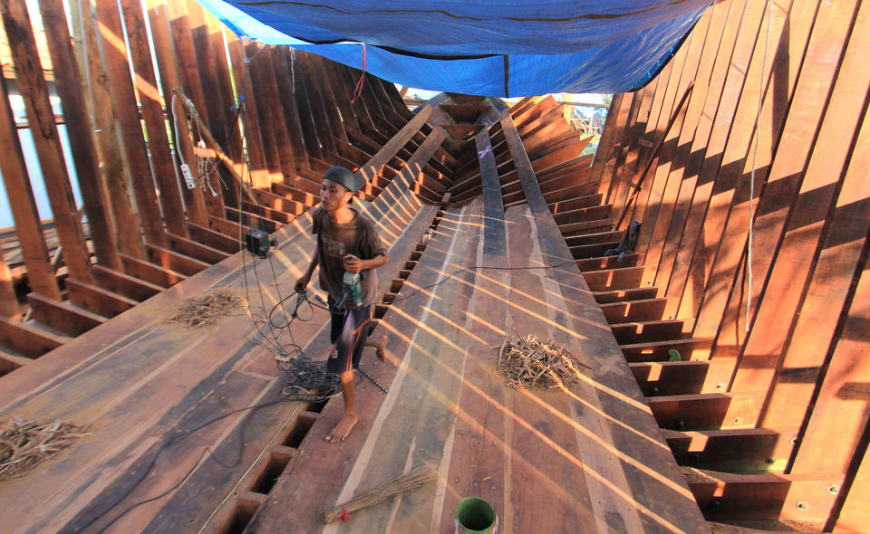 A worker walks inside the partially completed hull of a traditional fishing boat in Pabean Udik village in Indramayu, West Java, on Friday (12/05). The owner of the vessel expressed concern over the difficulties involved in obtaining commercial fishing permits. (Antara Photo/Dedhez Anggara)