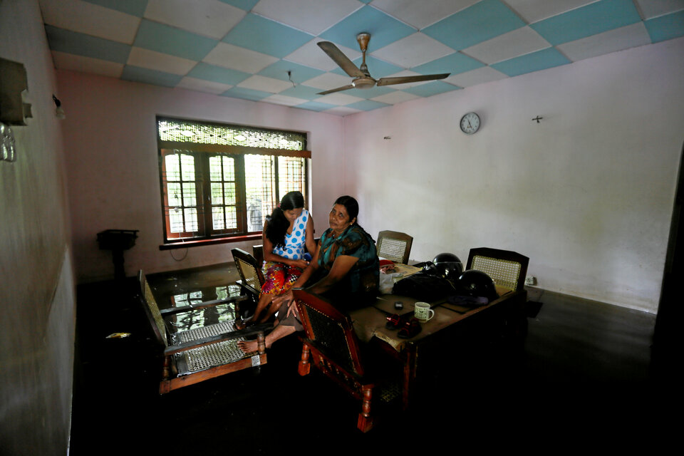 A family sits on a table inside their flooded house in Nagoda village in Kalutara, Sri Lanka, on May 29. (Reuters Photo/Dinuka Liyanawatte)