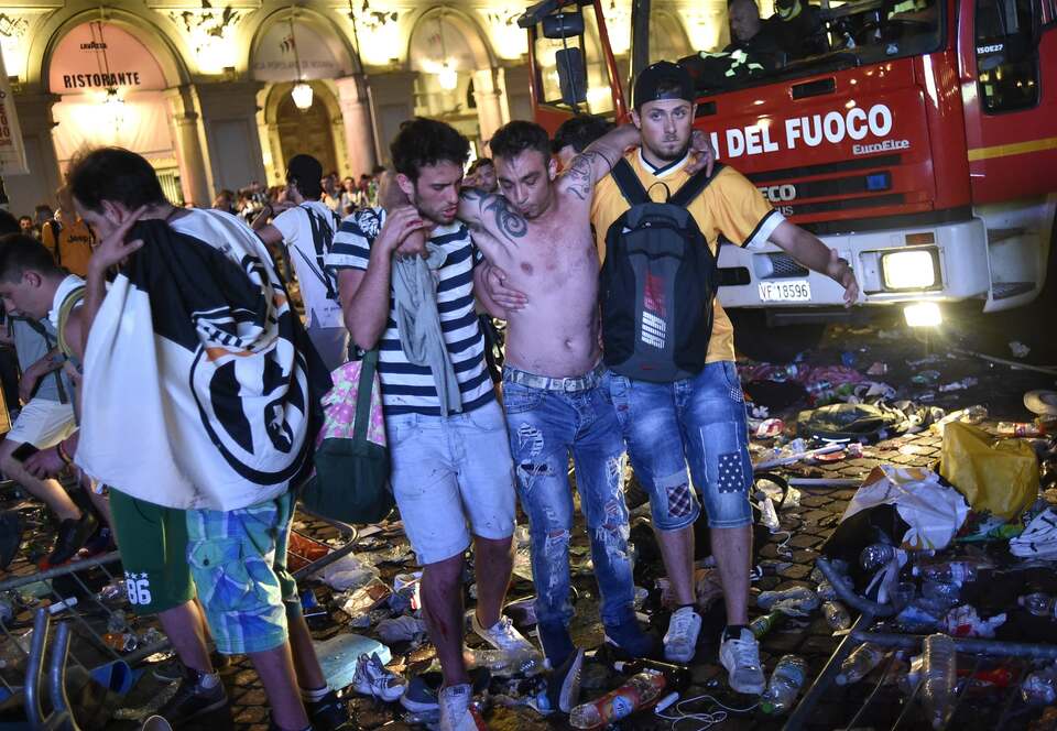 A Juventus fan is helped to walk as people gathered in San Carlo Square run away following panic created by the explosion of firecrackers. (Reuters Photo/Giorgio Perottino)