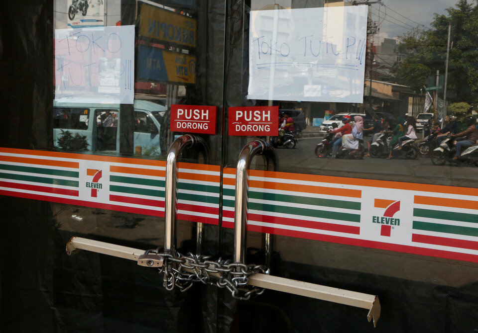 Chains are used to lock the front door of a 7-Eleven convenience store in Jakarta, Indonesia, on June 27, 2017. The signs say 'Shop Closed.' (Reuters Photo/Agoes Rudianto)