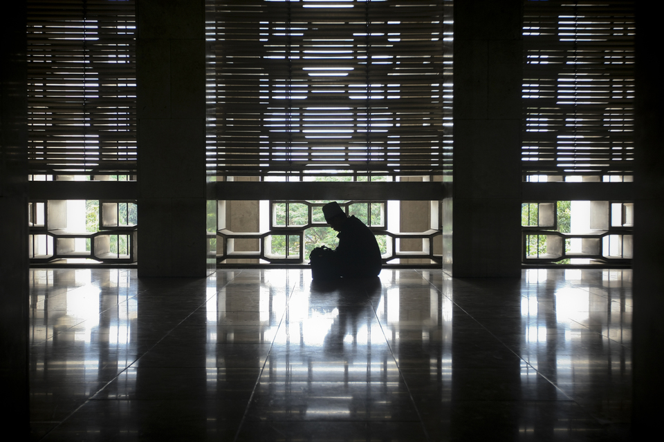 A man reads the Holy Koran as he waits for buka puasa, the time to break your fast during Ramadan, at Istiqlal Mosque in Central Jakarta on Monday (05/06). (JG Photo/Yudha Baskoro)