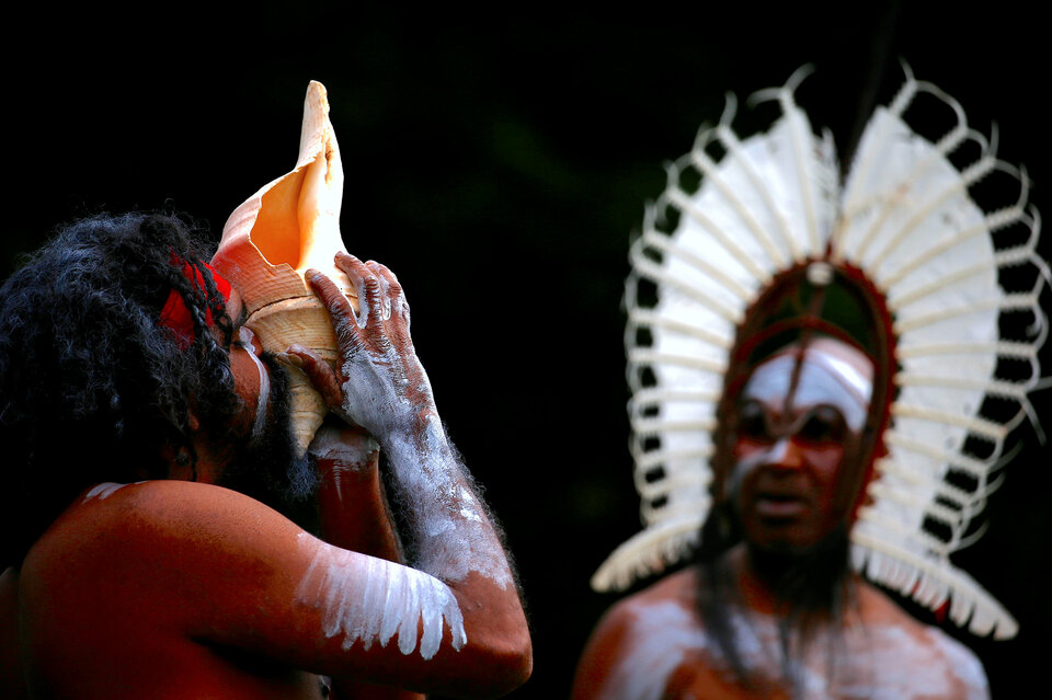 An Australian Aboriginal man blows into a shell as an indigenous man from the Torres Strait Islands wearing traditional dress performs during a welcoming ceremony at Government House in Sydney, Australia, June 28, 2017.  (Reuters Photo/David Gray)